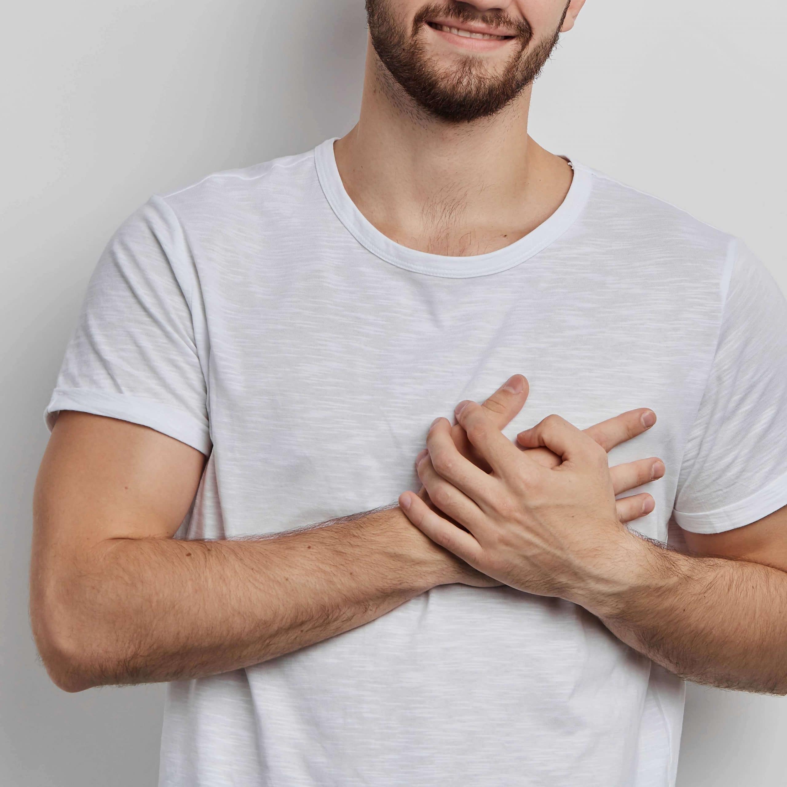 Hombre joven de frente, llevándose las dos manos a la altura del corazón